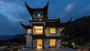 A traditional multi-story building with a prominent roof structure, large windows, and a well-lit entrance. - Leisure Haven - Tachuan Hotel (Huangshan)