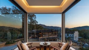A balcony with wicker chairs and a small table, overlooking a traditional courtyard and distant mountains. - Leisure Haven - Tachuan Hotel (Huangshan)