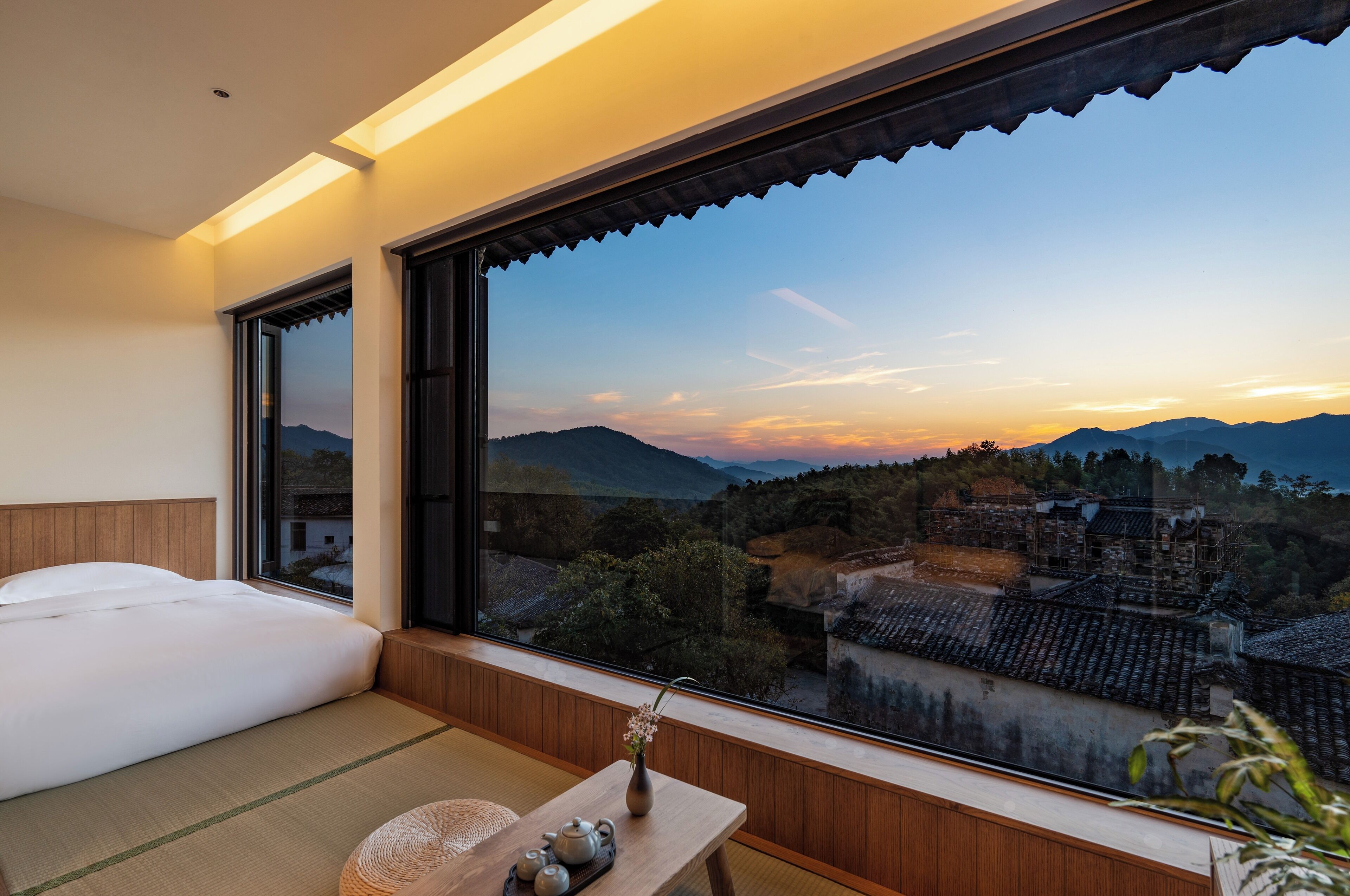 Una habitación con un ventanal que ofrece vistas a edificios tradicionales y montañas.