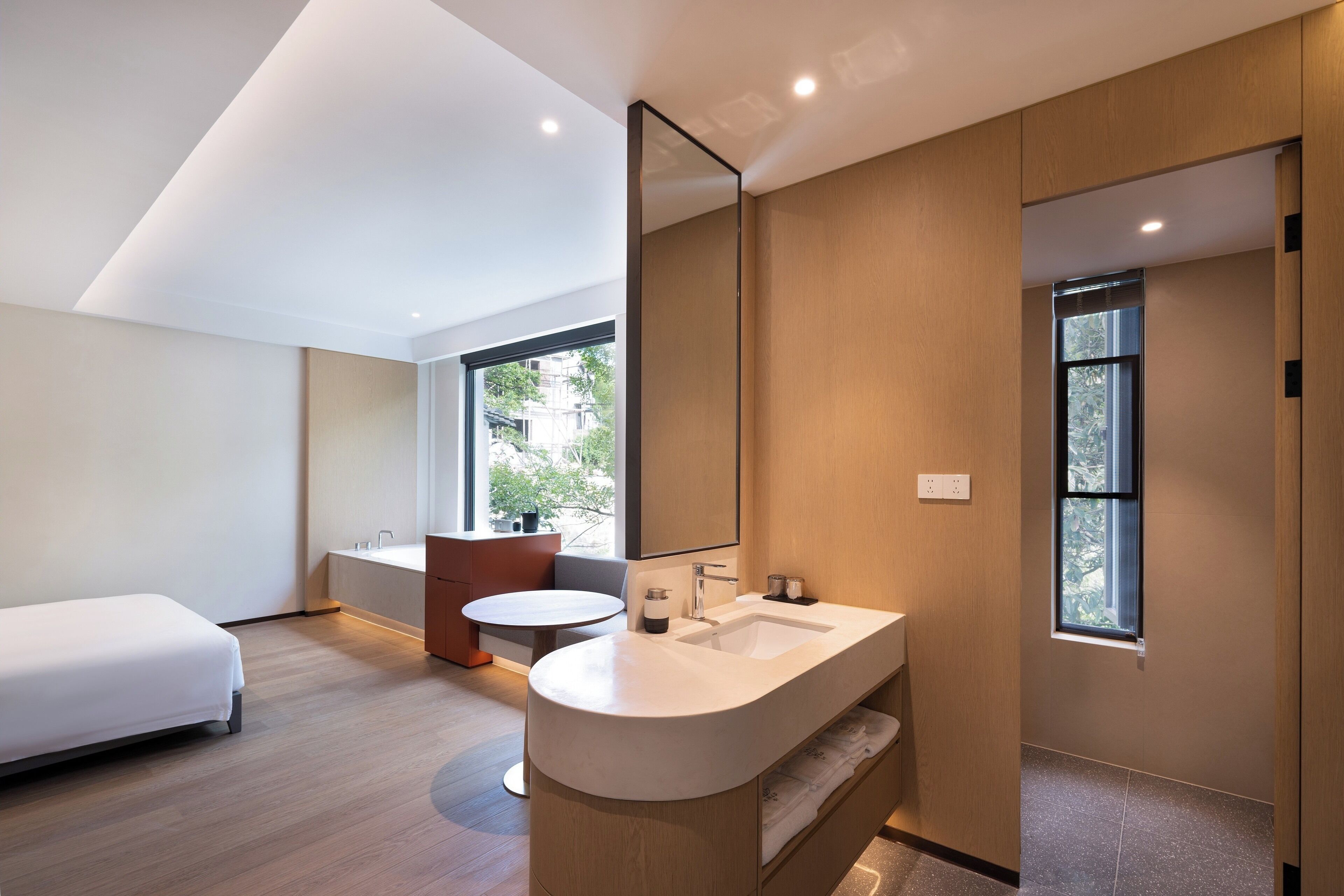 Un baño moderno con un espejo grande, un lavabo y un inodoro. En la habitación hay una cama y una ventana.