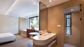 Un baño moderno con un espejo grande, un lavabo y un inodoro. En la habitación hay una cama y una ventana.