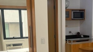 Habitación de hotel con cama, baño, kitchenette y vista al exterior.