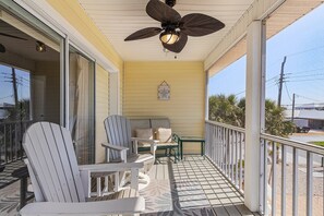 A covered porch with a ceiling fan, a table, and two Adirondack chairs. - King Suite & Patio|Family & Furry-Friendly Escape (Fort Myers Beach)