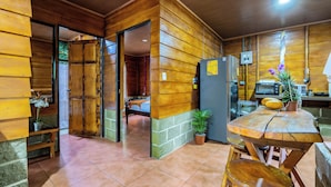 Una cocina compacta con paredes de madera, una mesa de comedor, sillas, un refrigerador, un microondas y una planta en maceta.