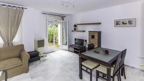 Una sala moderna con sofá, una mesa de comedor con sillas, un televisor y un mueble bajo.