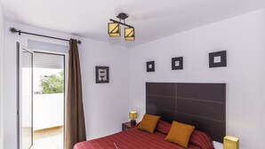 Un dormitorio con una cama grande, una puerta corrediza de vidrio a un balcón y un cabecero moderno.