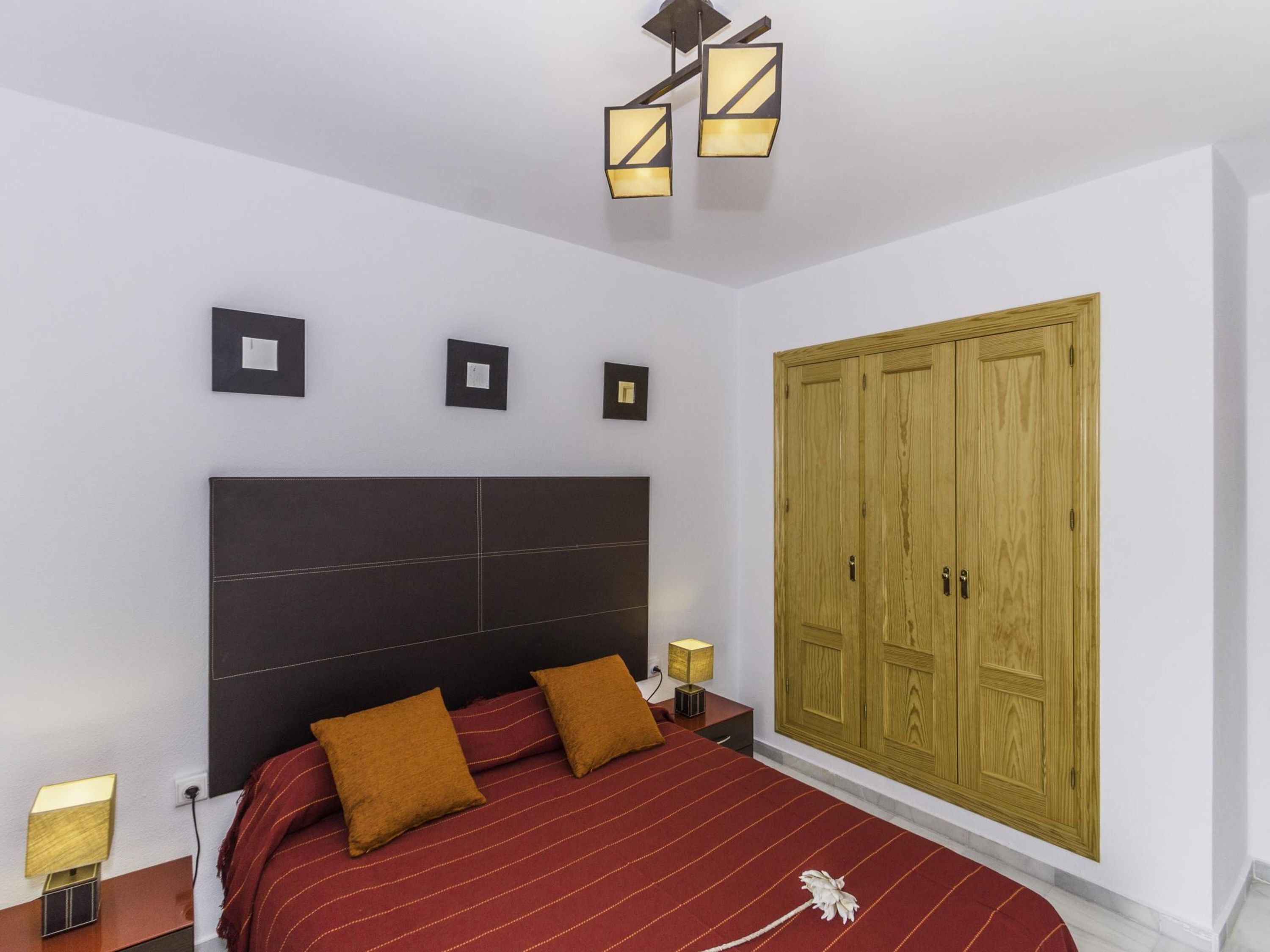 Ein Schlafzimmer mit einem großen Bett, einem Holzschrank und einer modernen Leuchte.
