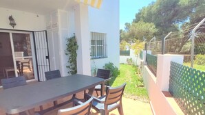 A patio with a table and chairs, a sliding glass door, and a small garden area with a fence. - Rotonda VII 54 in Conil de la Frontera (Conil de la Frontera)