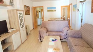 A living room with a sofa, a coffee table, a TV, and a radiator. - Rotonda VII 54 in Conil de la Frontera (Conil de la Frontera)