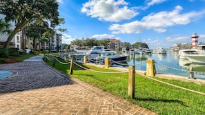 A marina with boats docked, a lighthouse, and buildings in the background.