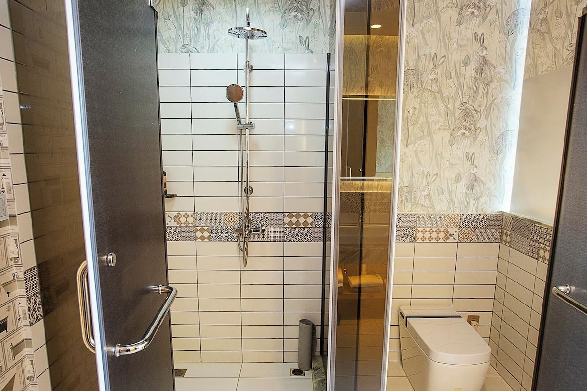 A bathroom with a shower, toilet, and a glass door.