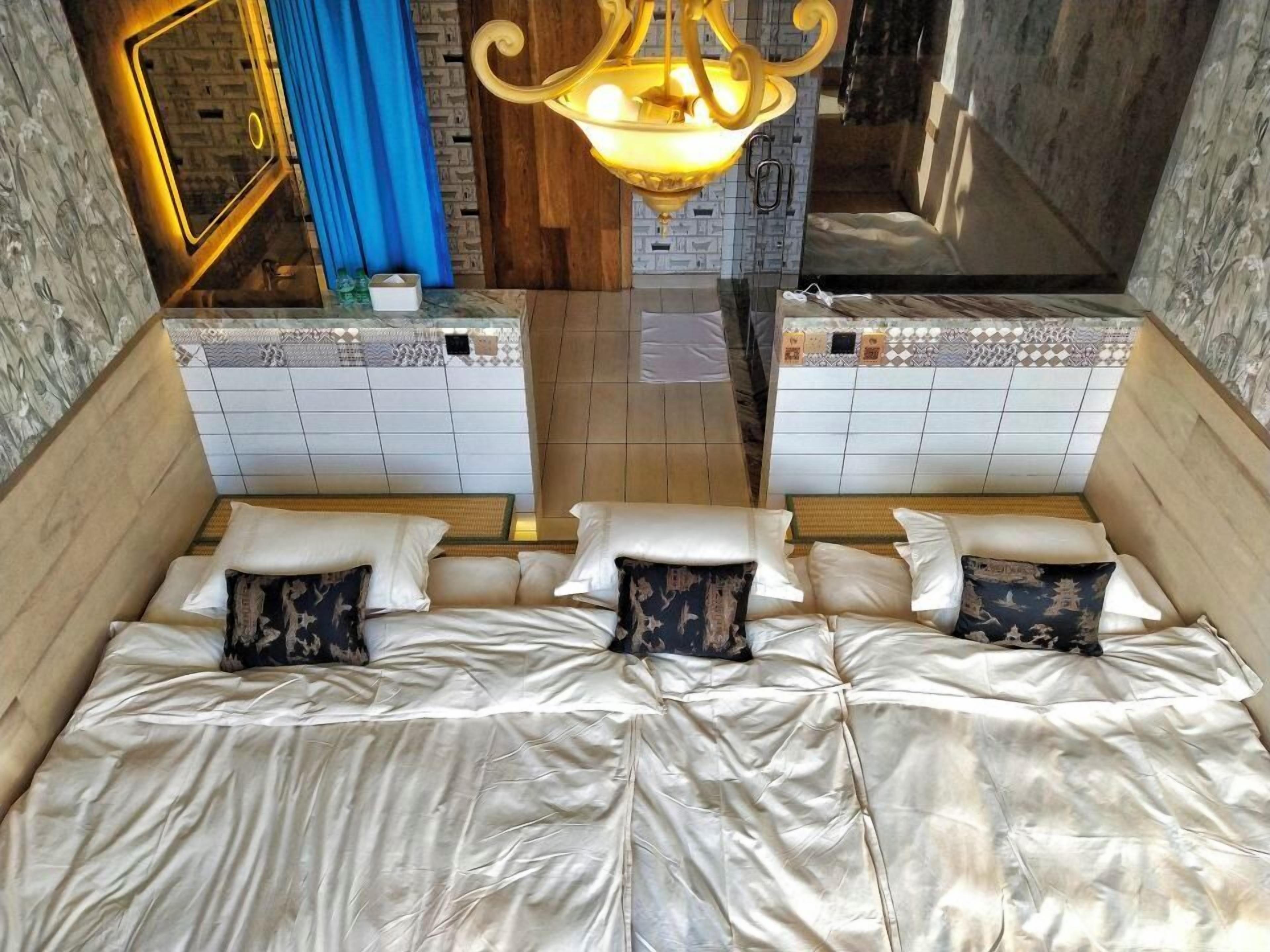 Una habitación con una cama grande, dos mesitas de noche, un espejo y una araña.