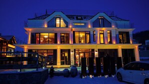 Une maison moderne à deux étages, dotée d’une piscine et d’une voiture garée devant.