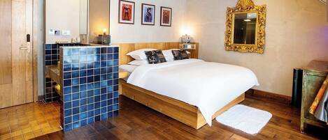 A bedroom with a wooden bed, a blue-tiled sink, a mirror, and framed pictures on the wall.