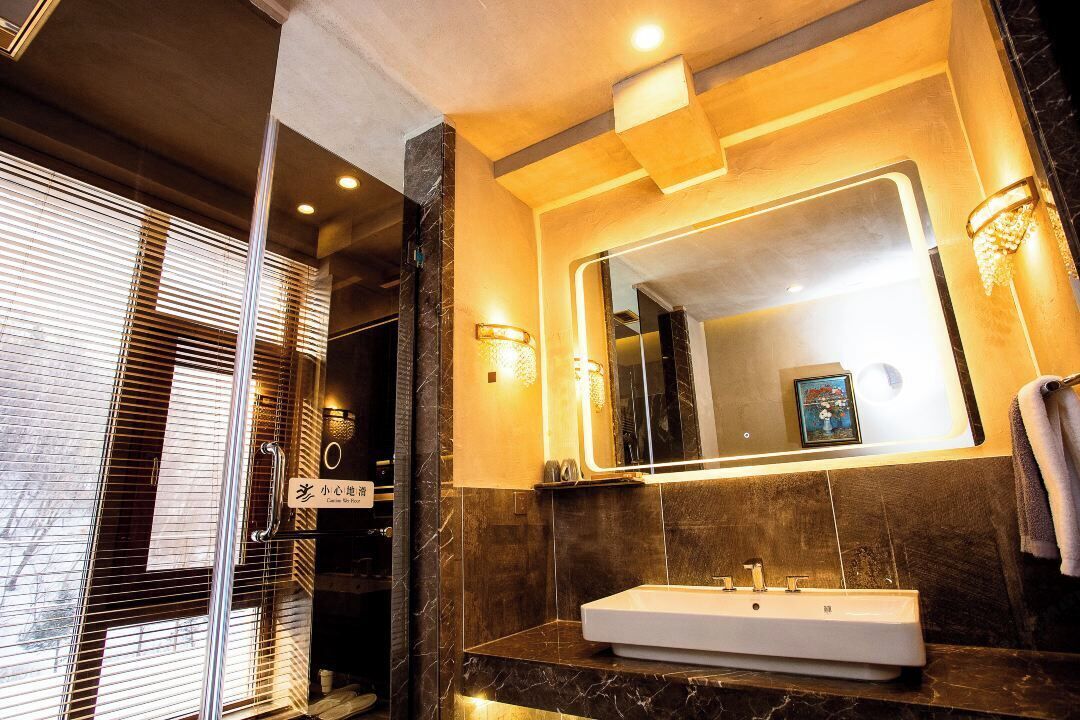 A modern bathroom with a large mirror, a white sink, and a shower area.