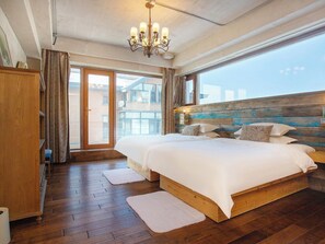 A bedroom with a wooden headboard, a large bed with white bedding, a chandelier, and a view of the outside. - Shangzhi Qushe Resort Hotel (Harbin)