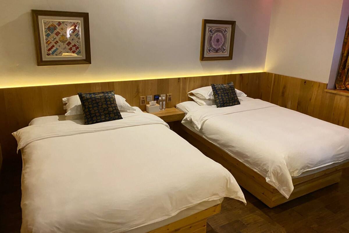 Two single beds with wooden headboards, white bedding, and a nightstand with a lamp and a tissue box.