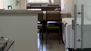 Une cuisine avec un coin repas, une fenêtre avec des rideaux et un réfrigérateur.