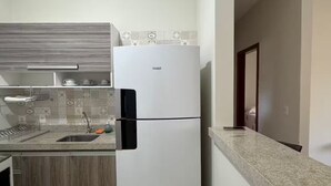 Une cuisine de taille réduite avec un réfrigérateur blanc, un plan de travail en bois et un pare-feu en carreaux.