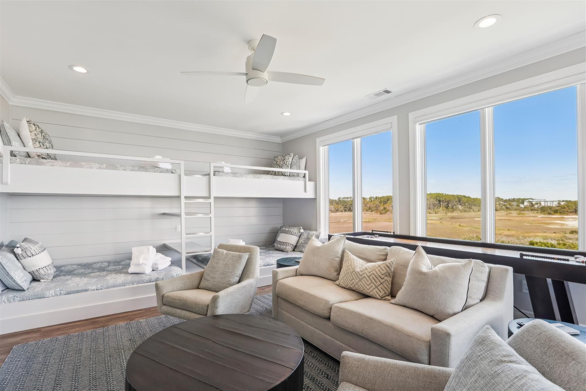 A modern living room with bunk beds, a sofa, and a view of the outdoors.