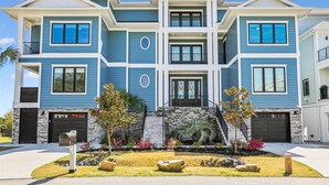 A two-story residential building with a stone facade, multiple windows, and a front entrance. - 8 Sea Front, Oceanfront Estate, Pool, Huge Game Room, Elevator (Hilton Head Island)