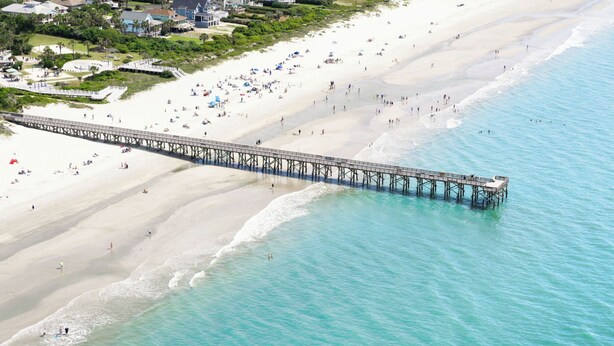 A pier extending into a beach with people and houses in the background. - Unforgettable marsh views 4 bedroom home (North Charleston)