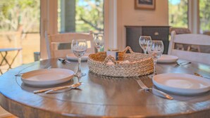 A round dining table set with white plates, cutlery, and wine glasses, with a woven basket in the center. - Unforgettable marsh views 4 bedroom home (North Charleston)