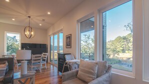 A spacious living room with a large window, a chandelier, and a view of the outdoors. - Unforgettable marsh views 4 bedroom home (North Charleston)