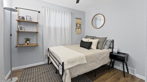 A bedroom with a bed, bedside table, and a ceiling fan.