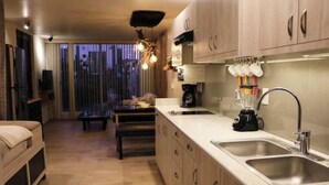 A modern kitchen with a large island, double sink, and a dining area with a table and chairs. - Rincon Canela: Comfortable apartment in Morelia, close to the historical center (Morelia)