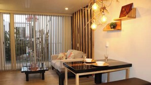 A modern living room with a glass dining table, a sofa, and a bench. There is a sliding glass door leading to an outdoor area. - Rincon Canela: Comfortable apartment in Morelia, close to the historical center (Morelia)