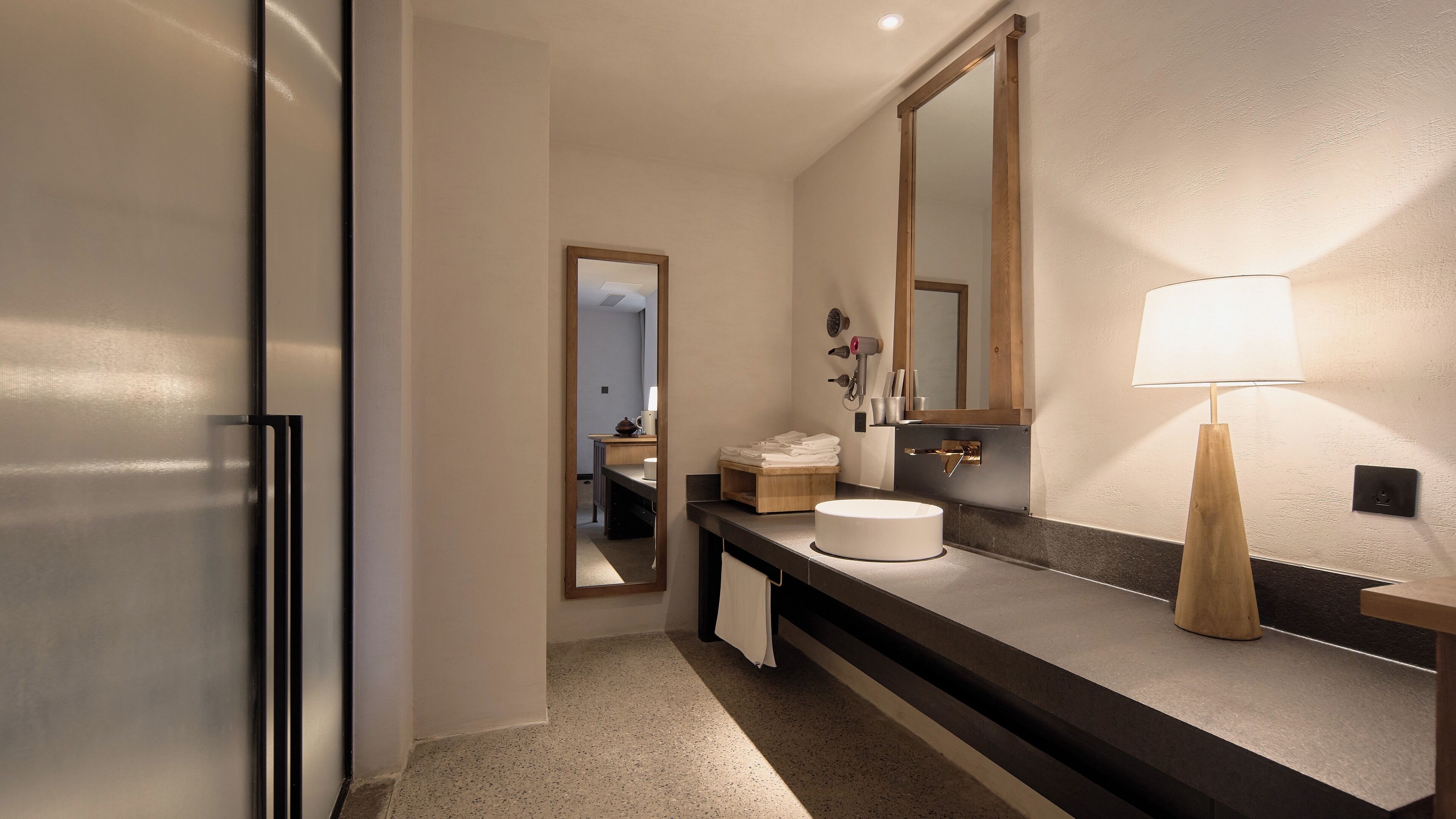 A modern bathroom with a large mirror, a round sink, and a towel rack.