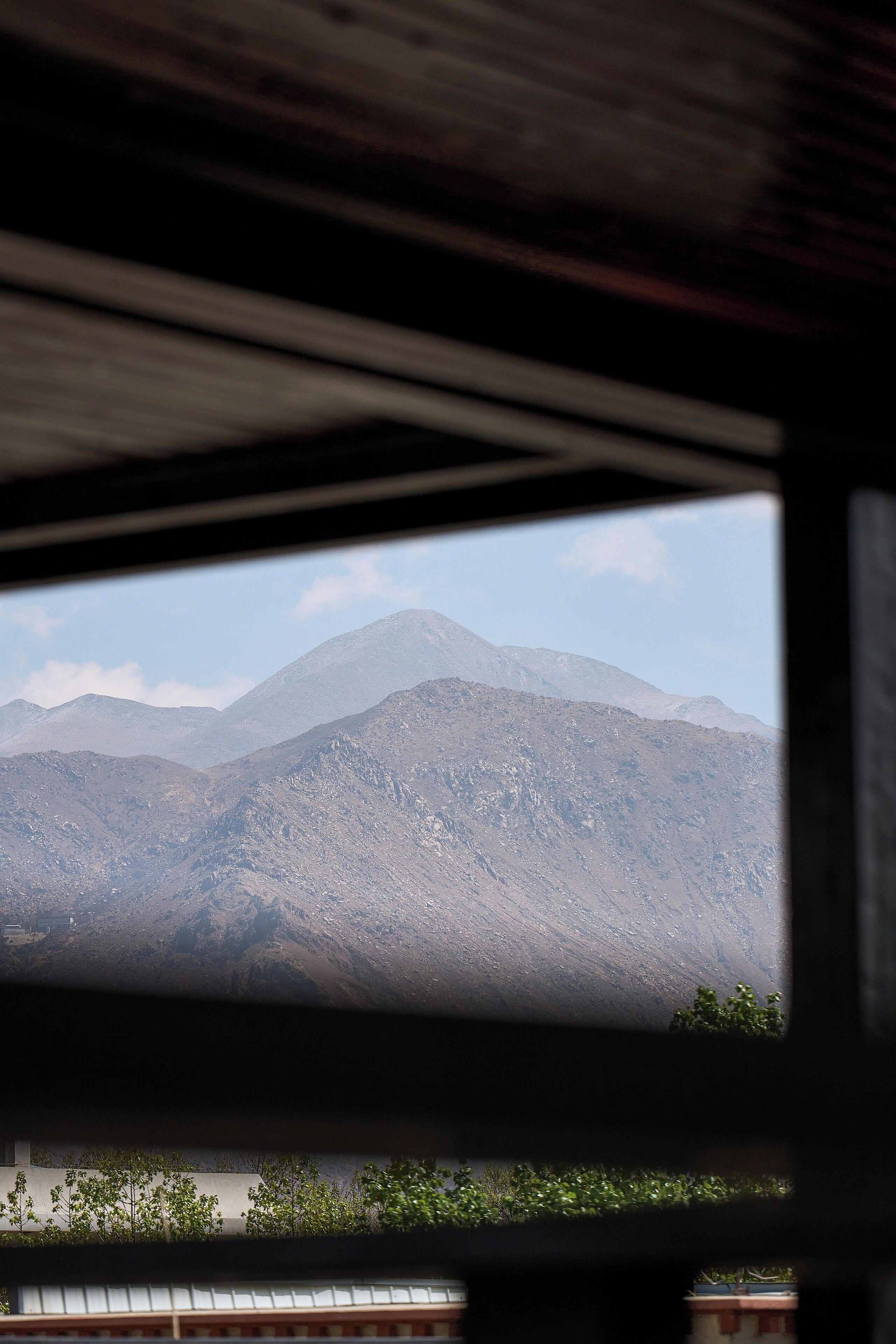 A view through a window of a mountainous landscape with a building in the foreground.