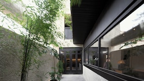 Een modern gebouw met een glazen gevel, een betonnen buitenkant en een kleine binnenplaats met planten in potten.