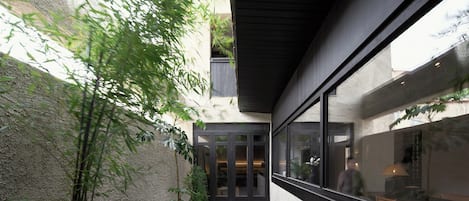 A modern building with a glass facade, a concrete exterior, and a small courtyard with potted plants.