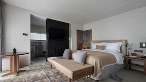 Een moderne hotelkamer met een bed, een bank, een bureau en een televisie.