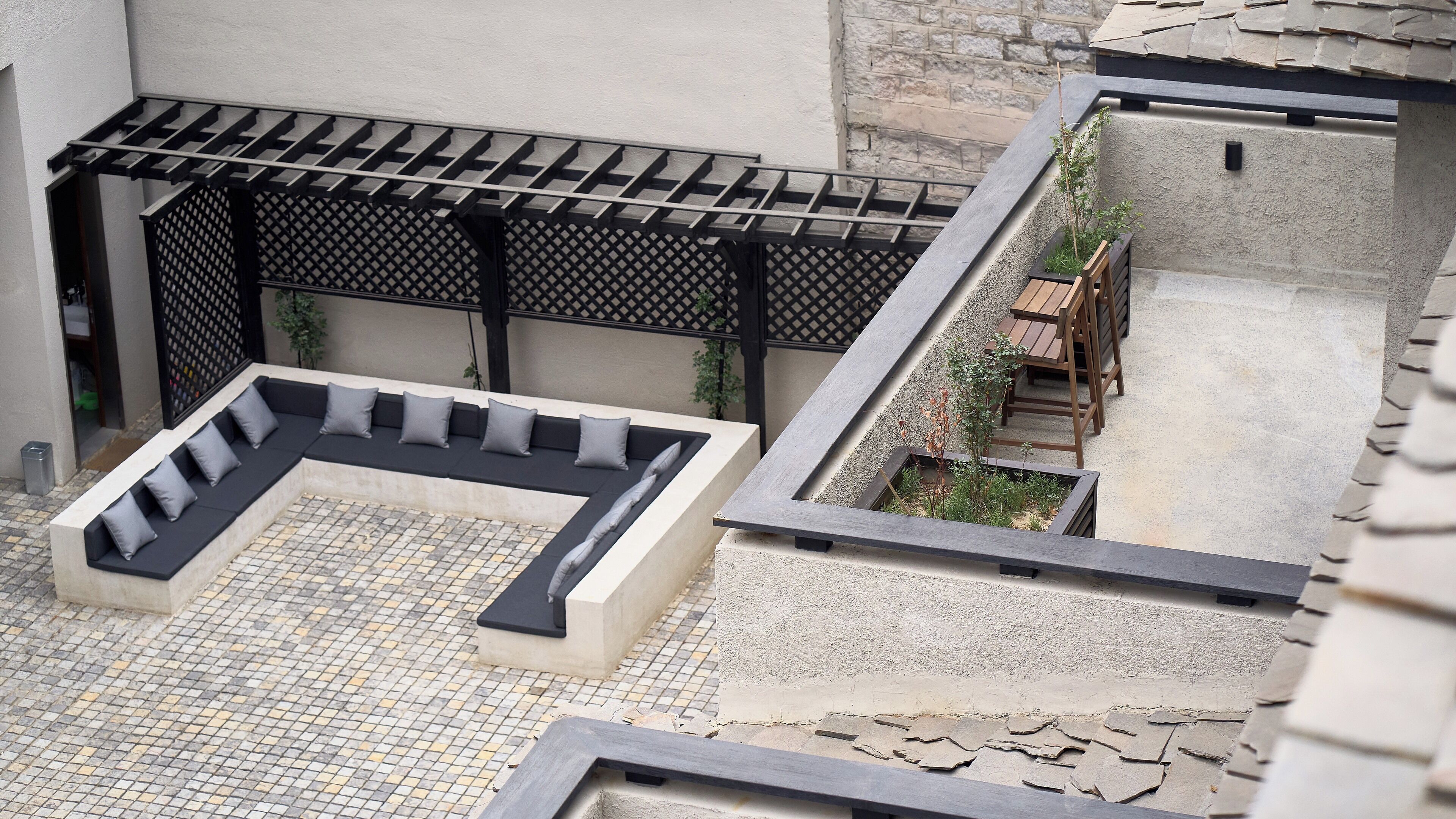 A courtyard with a seating area, a small garden, and a wooden table.