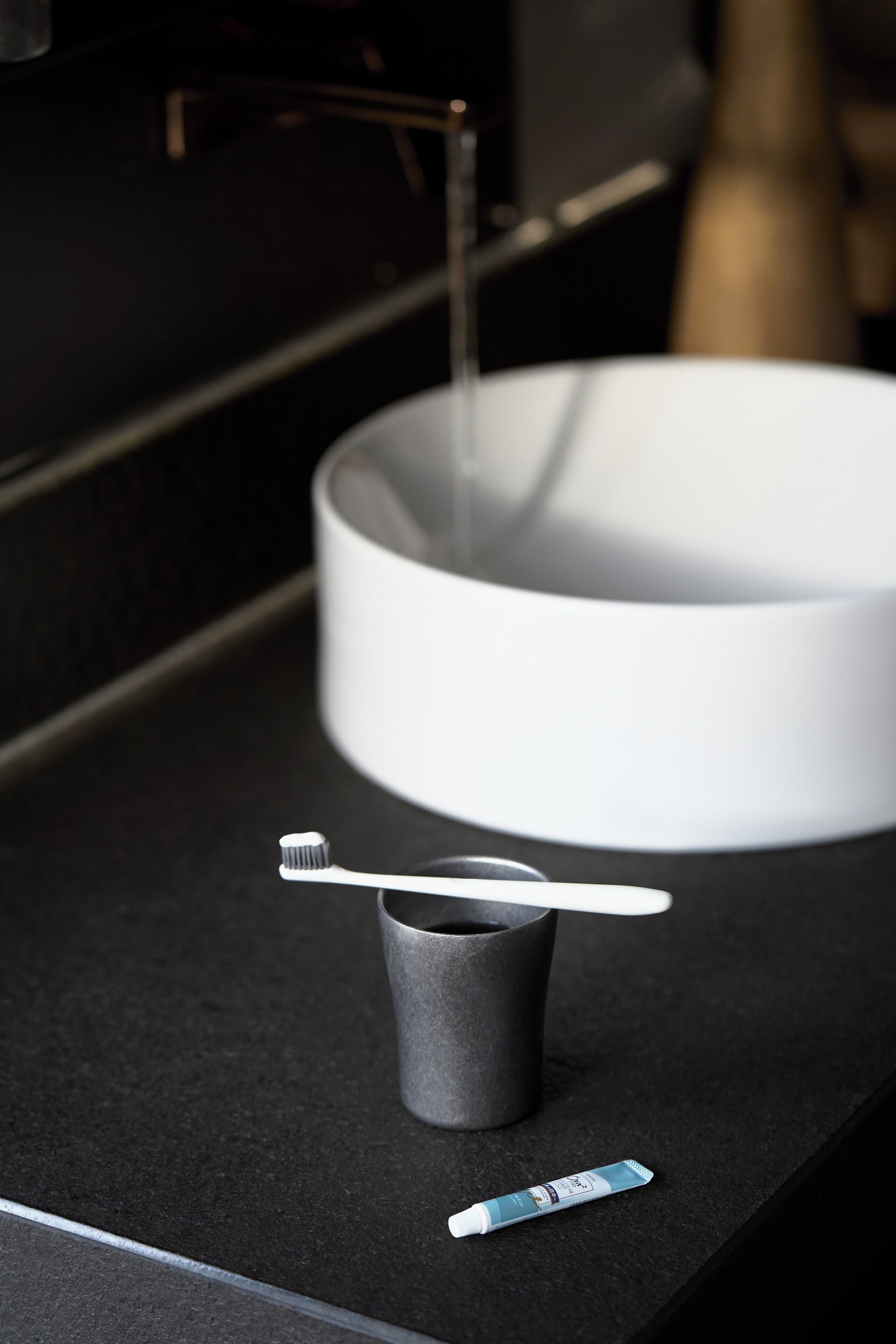 A bathroom sink with a toothbrush and toothpaste tube on the counter.