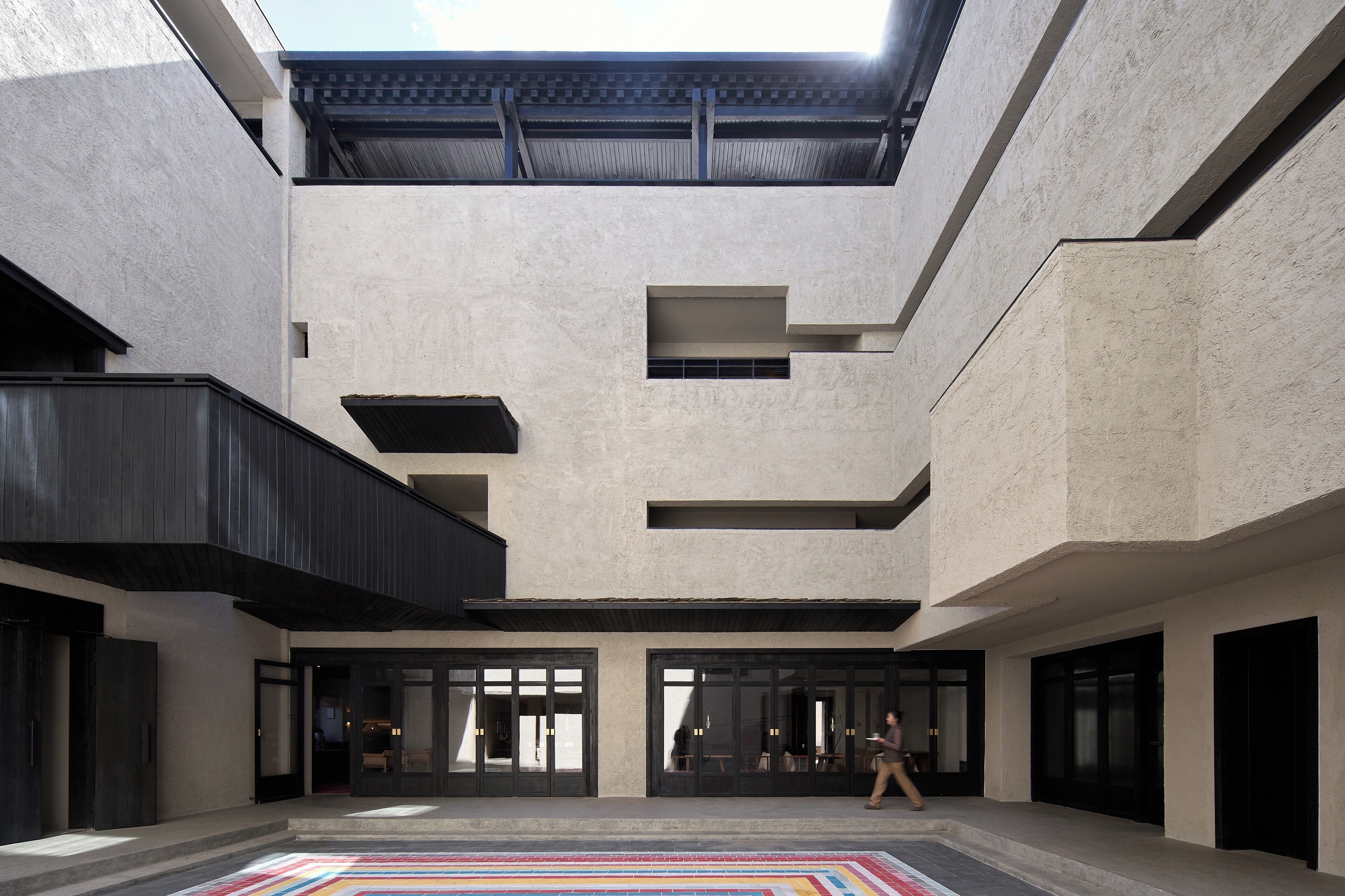 Un edificio moderno con un patio central, ventanas amplias y techo plano.