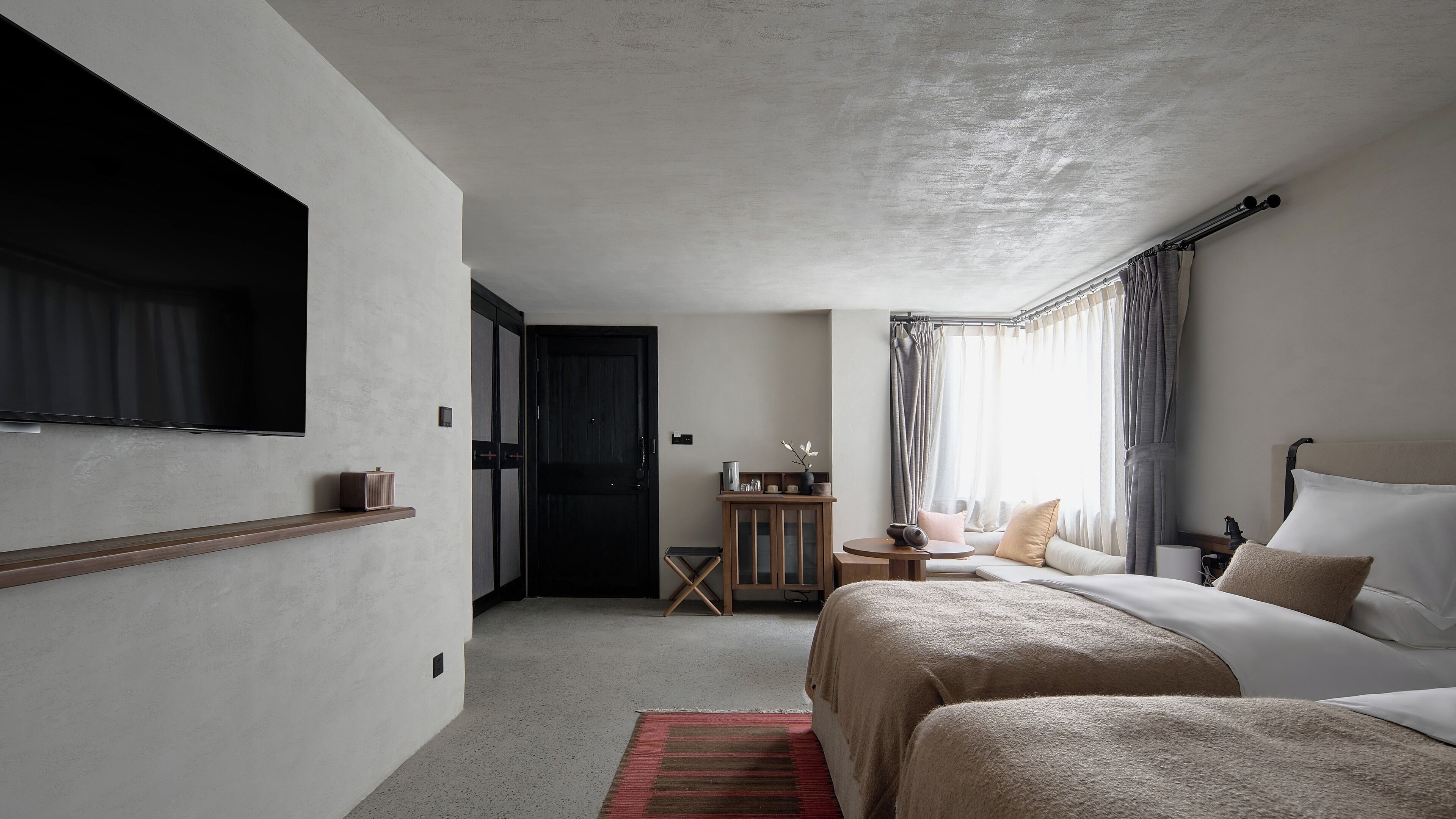 Une chambre d’hôtel comprenant un lit, une table de chevet et un petit coin salon avec une table et des chaises.