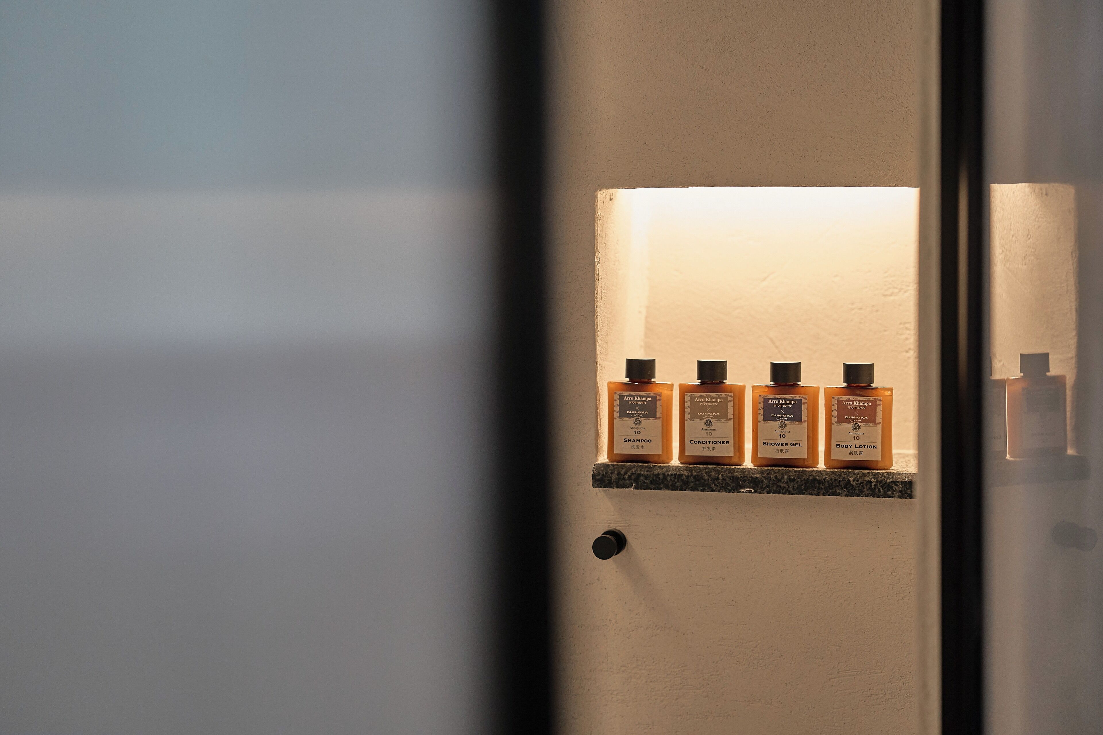 Une étagère de salle de bain avec trois bouteilles de shampoing, d’après-shampoing et de gel douche.