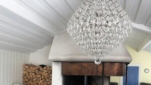 A cozy room with a fireplace, a chandelier, and a stack of firewood. - Stockholm  Archipelago – Idyllic Island (Värmdö)