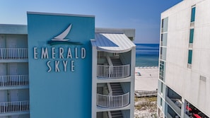 Un hotel con un letrero que dice 'Emerald Skye', con un balcón que ofrece vistas a la playa y al océano.