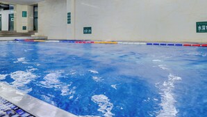 Ein Swimmingpool mit klarem, blauen Wasser, umgeben von einer gefliesten Terrasse und einer Holzbeschichtung.