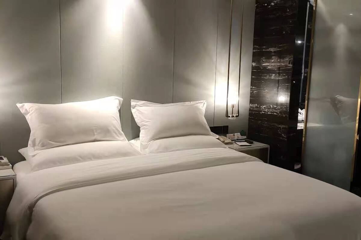 Une chambre d’hôtel moderne avec un grand lit, des tables de chevet, une coiffeuse avec un miroir et une baignoire.