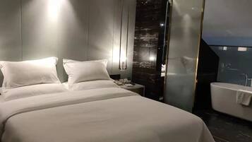 Una habitación de hotel moderna con una cama grande, mesitas de noche, un tocador con espejo y una bañera.