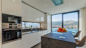 A modern kitchen with a Bosch oven, a large window with a city view, and a bar area with fruit.