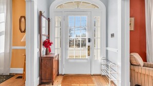 A hallway with a white door, a wooden cabinet, and a red wall. - Lakeside Vintage Retreat | Classic RVA Charm (Henrico)