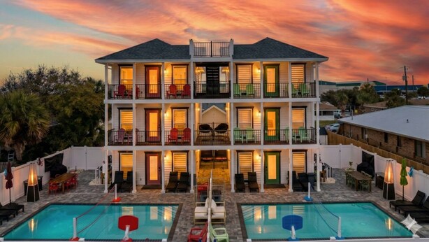 A two-story building with a pool area in front, featuring multiple balconies and outdoor seating.