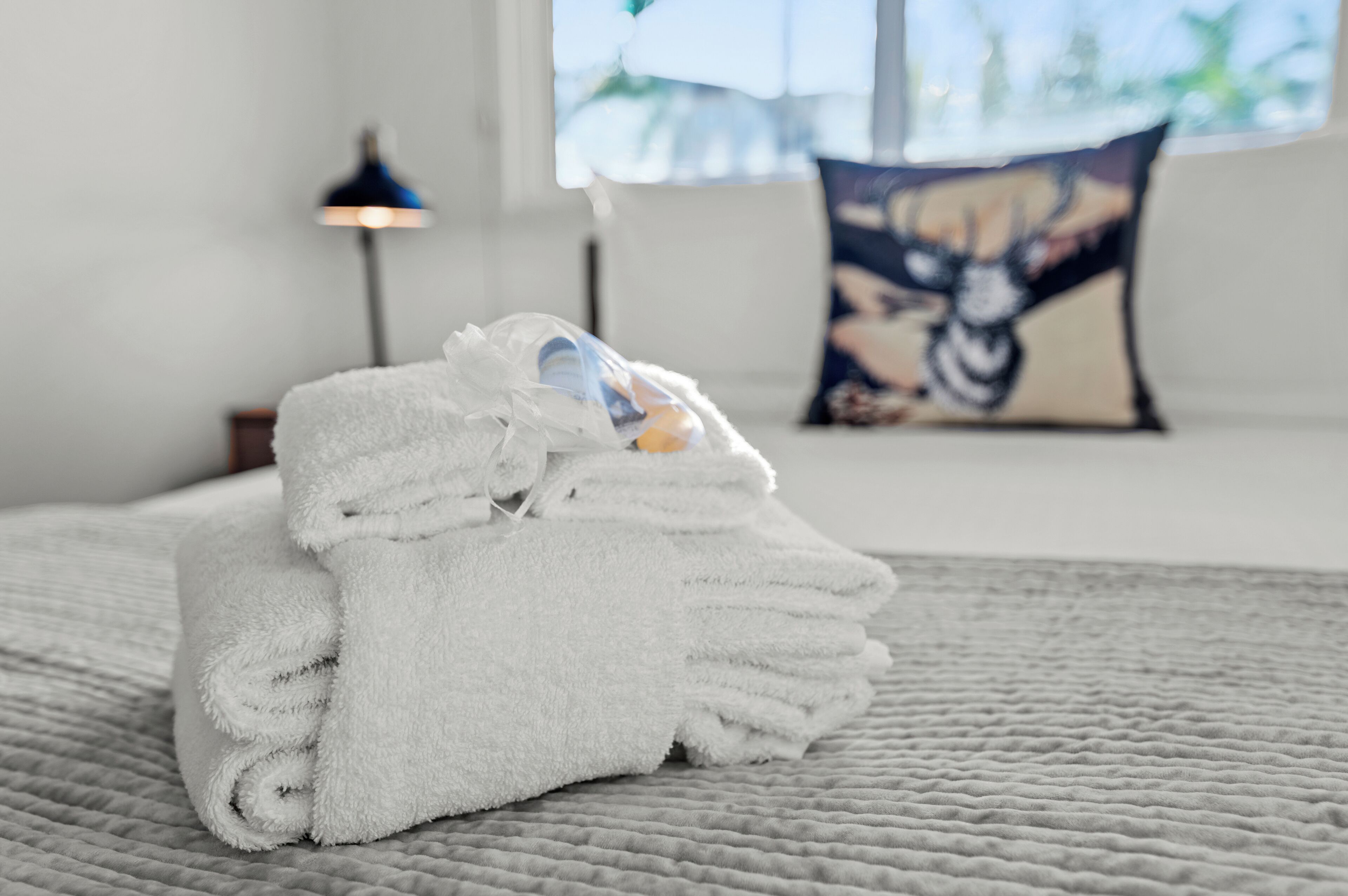 A neatly folded white towel on a bed with a textured blanket.